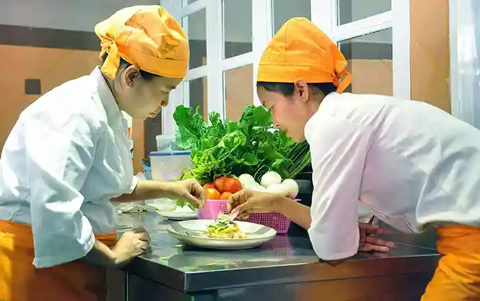 Twin chefs Kimsan sisters preparing a dish at their Embassy Restaurant in Siem Reap