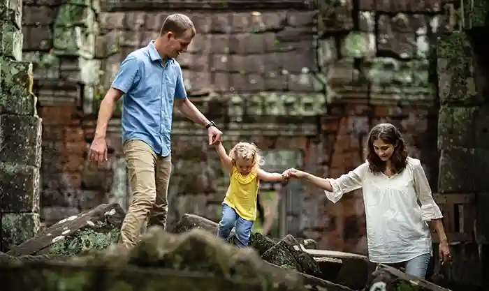 Family being photographed at Ta Phrom temple in Cambodia by Regis Bernard