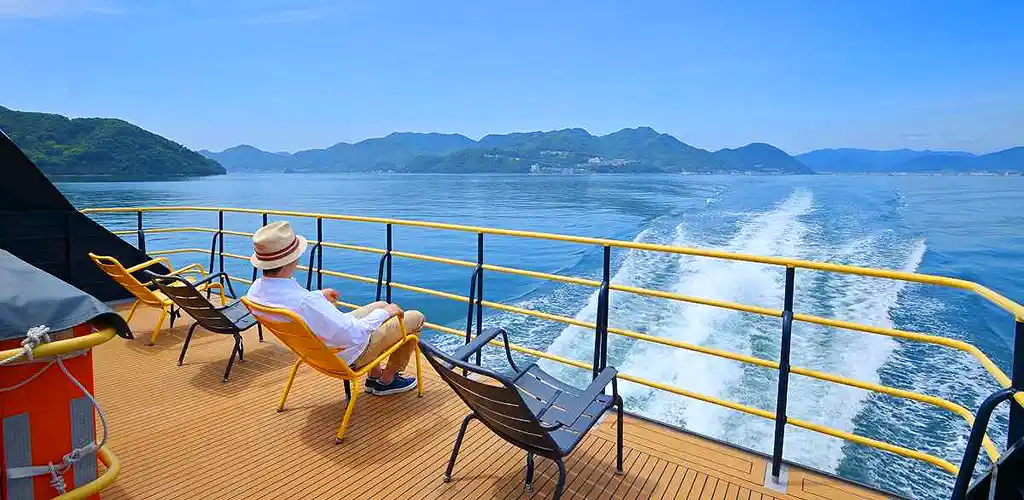 Passenger lounging on rear deck of cruise ship on the Seto Inland Sea