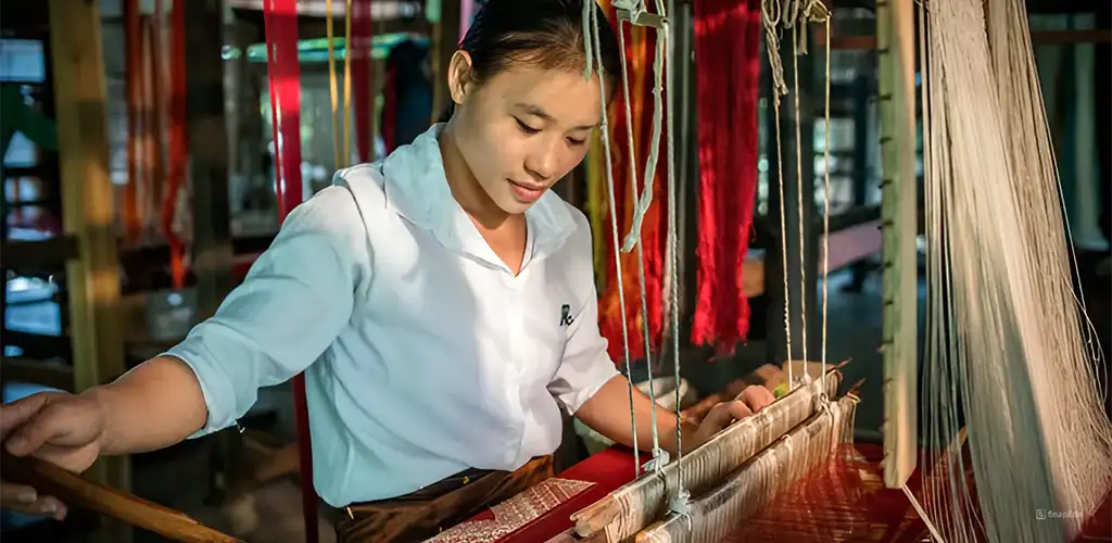 Laotian women working at weaving loom.