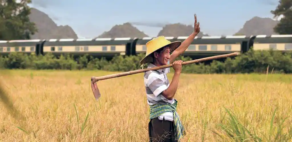 Malaysian farmer waving at Belmond Eastern & Oriental luxury train