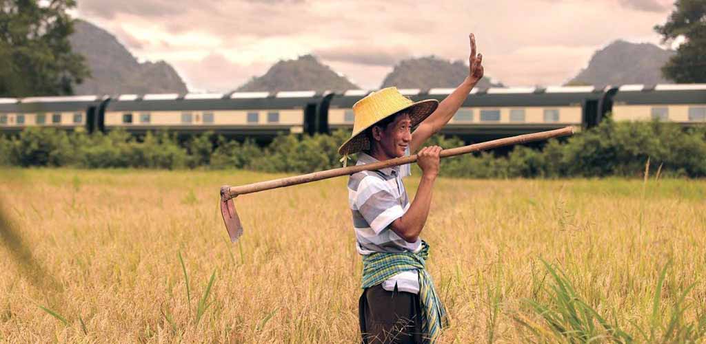 Eastern Orient Express luxury train passing by farmer in Thailand