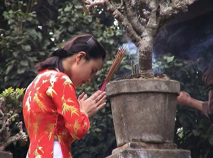 Girl burning incense at pagoda in Hanoi, Vietnam